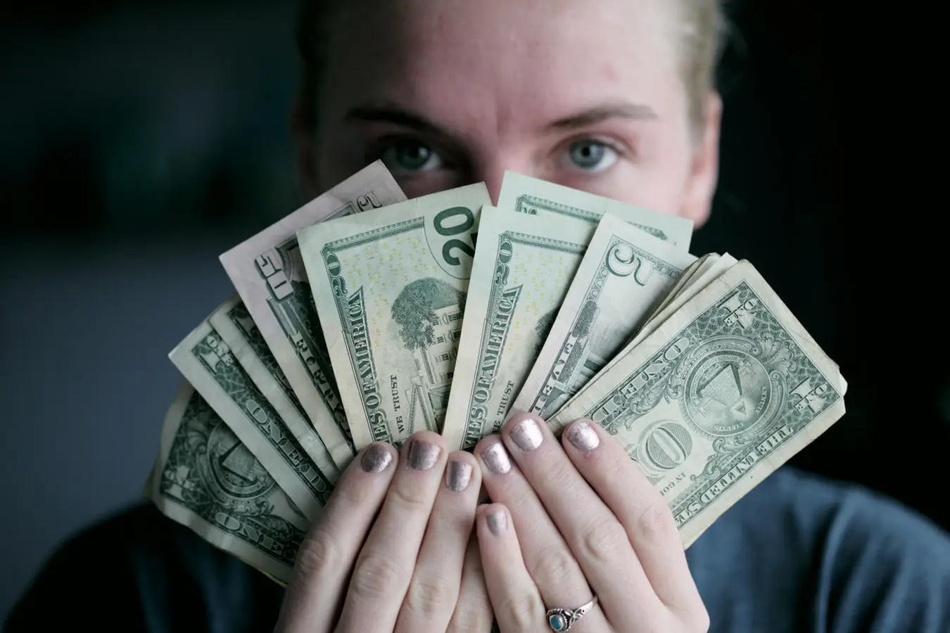 Girl with dollar bills in her hand and are placed over her face