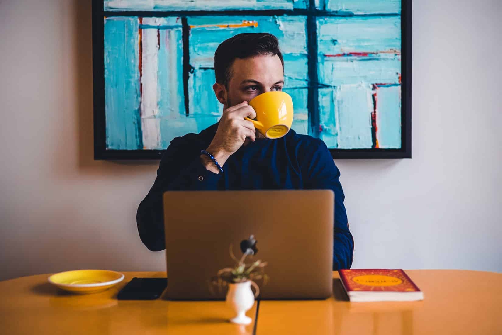 Man drinking coffee on his laptop