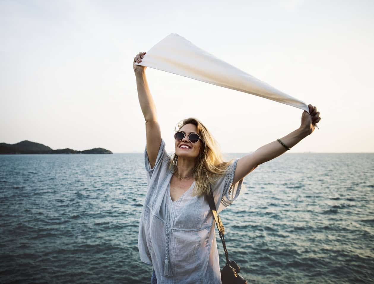 A lady smiling and happy with a white towel being held on top of her head