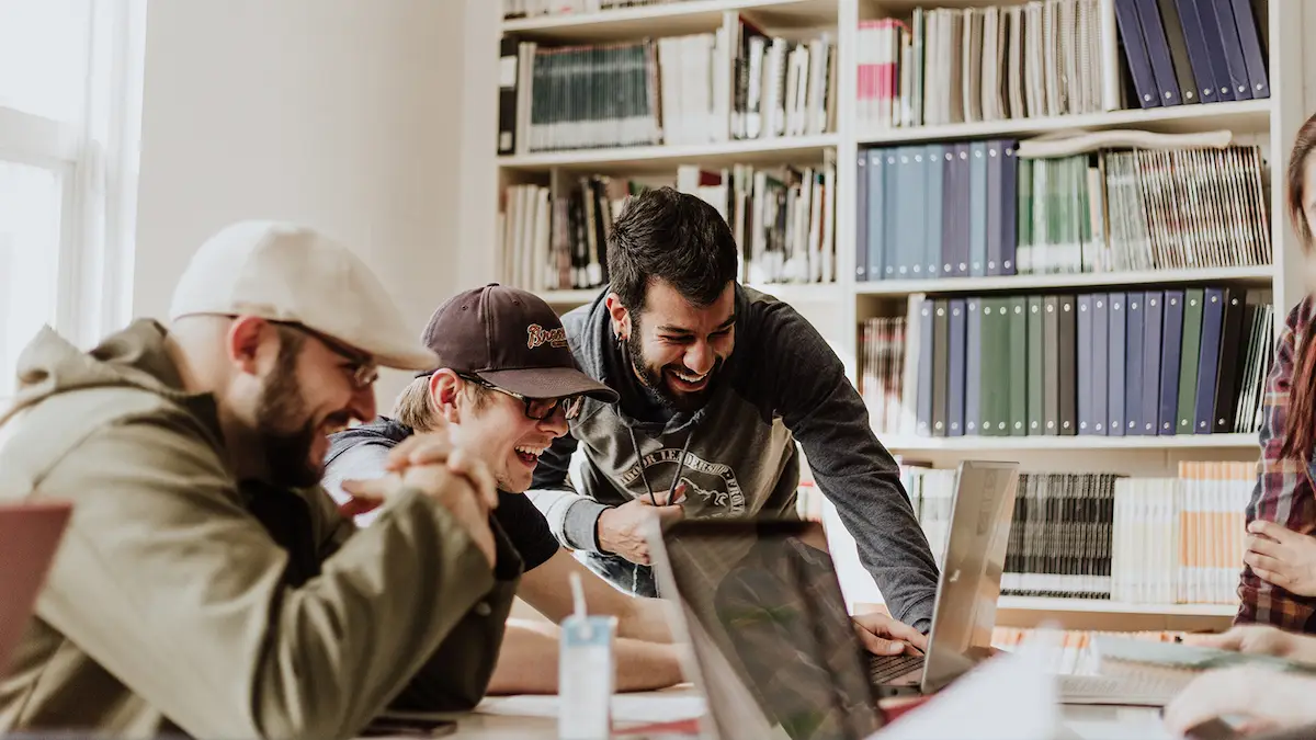 college kids laughing while looking at laptop