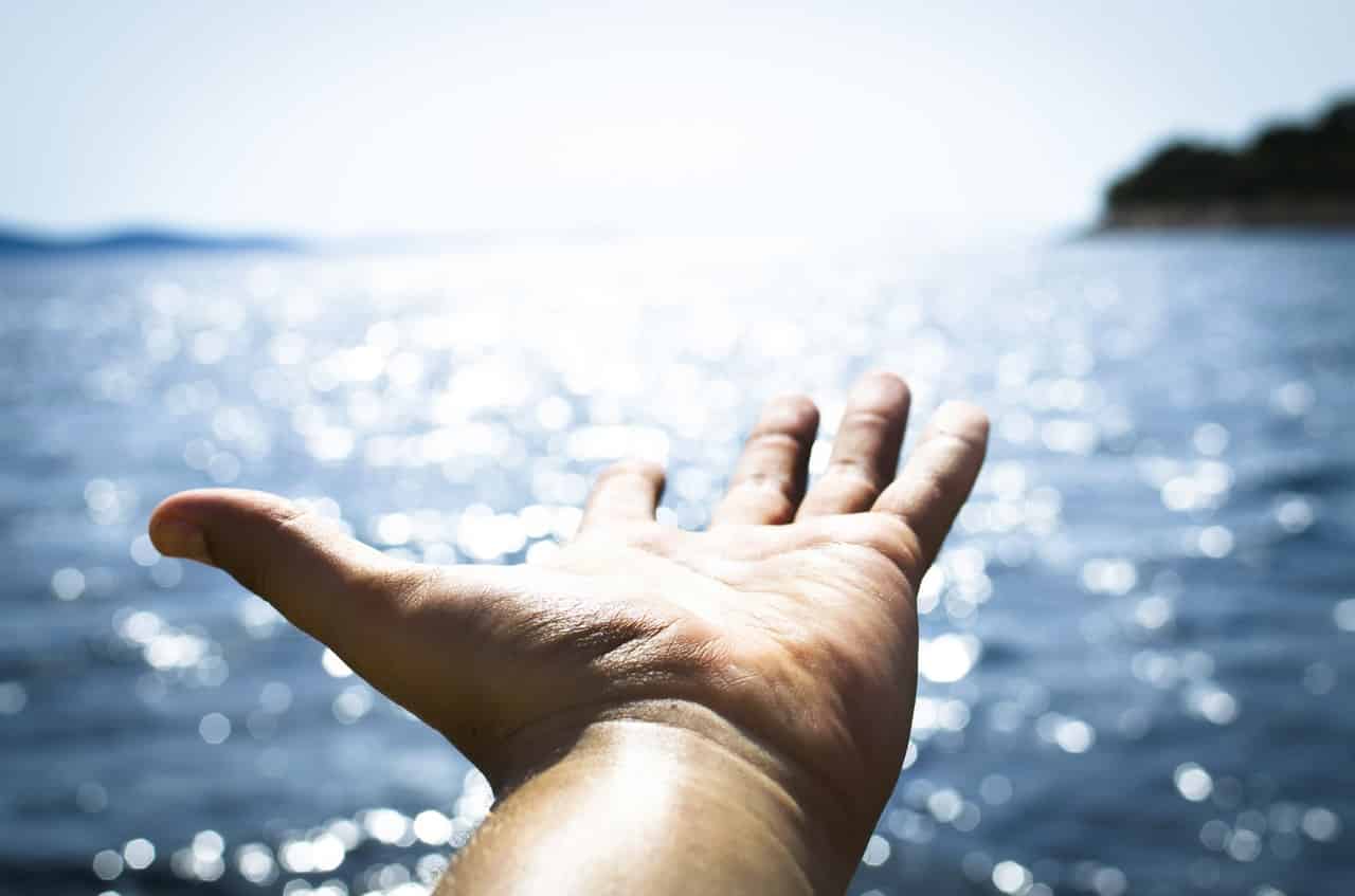 A man holding his hand out in front of water