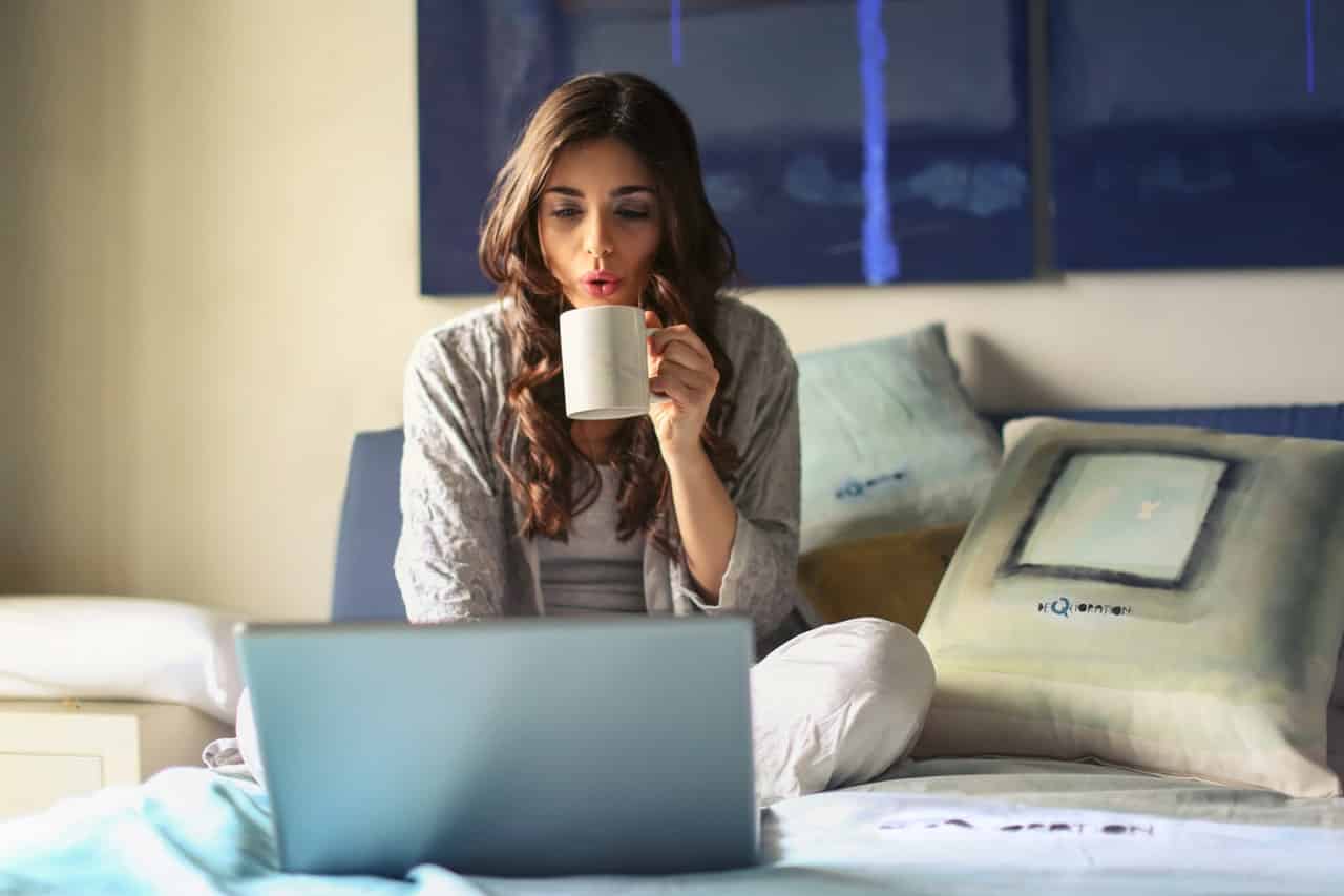 A girl on top of her bed with coffee