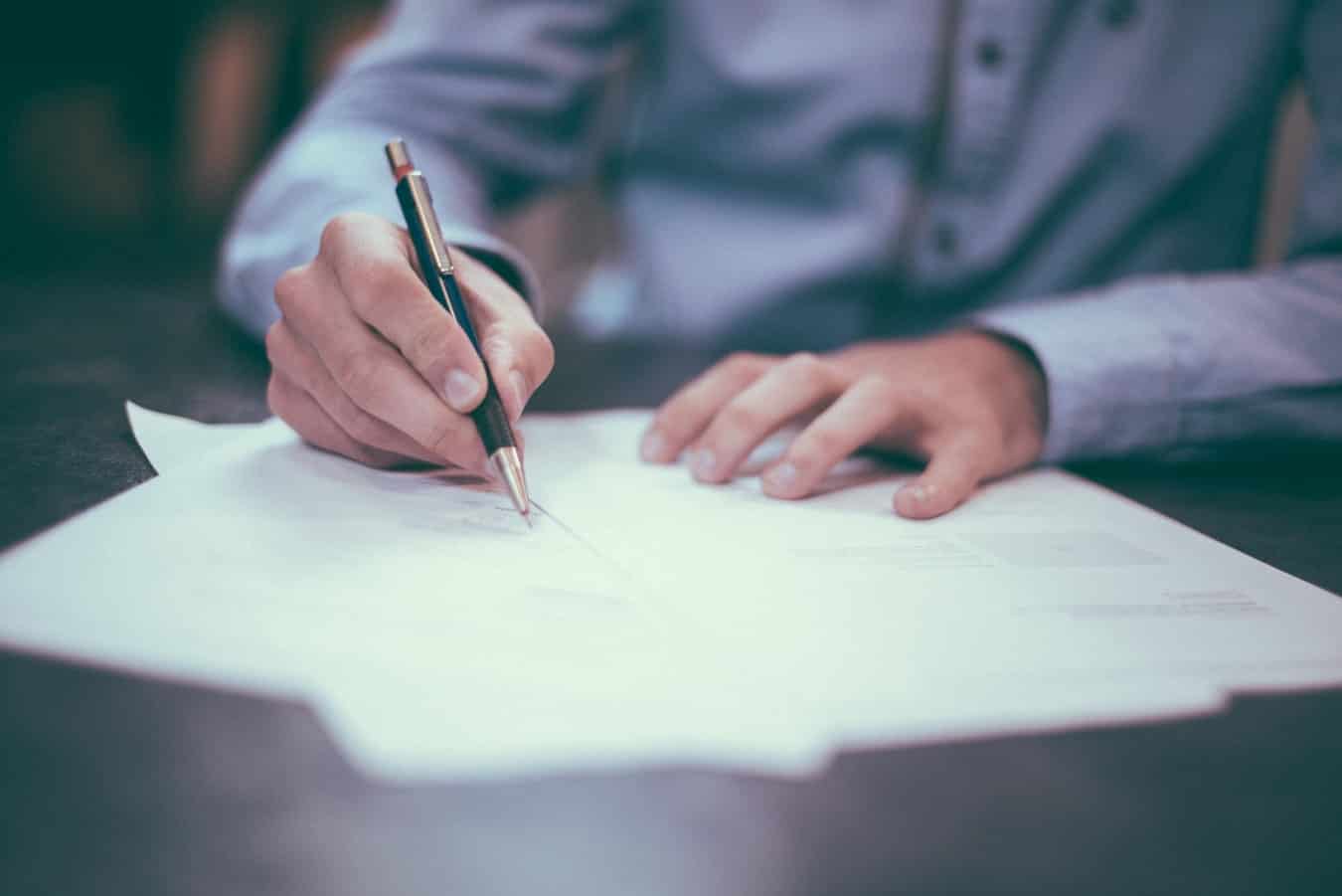 Man writing on paper on top of a table